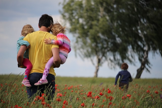 dad carrying his two kids while following his son in an open field, representing the article 'I Knew He Loved Me, Although He Couldn't Say It" by Comfortable Hell